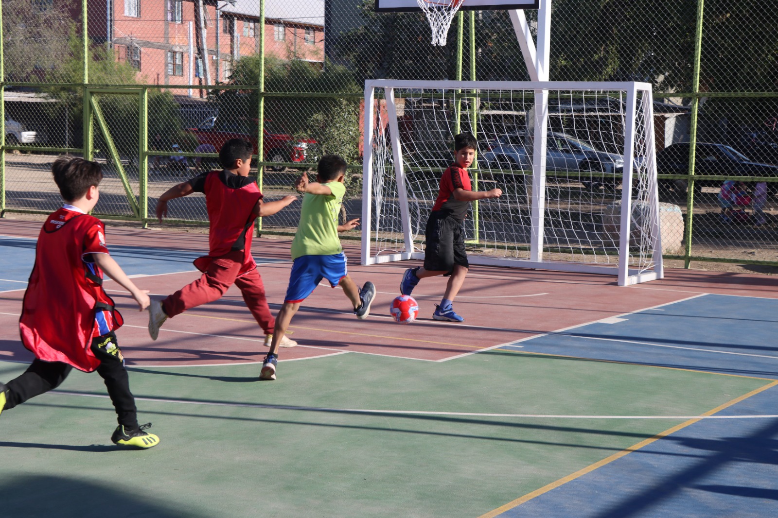 Niños y niñas del sector Villa Andes 1 jugando fútbol en la nueva multicancha de la Plaza Cárpatos durante el taller deportivo municipal.